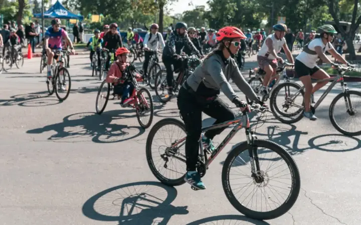 Grupo de ciclistas con casco pedaleando por una calle de la ciudad durante una salida de Ciclismo Urbano