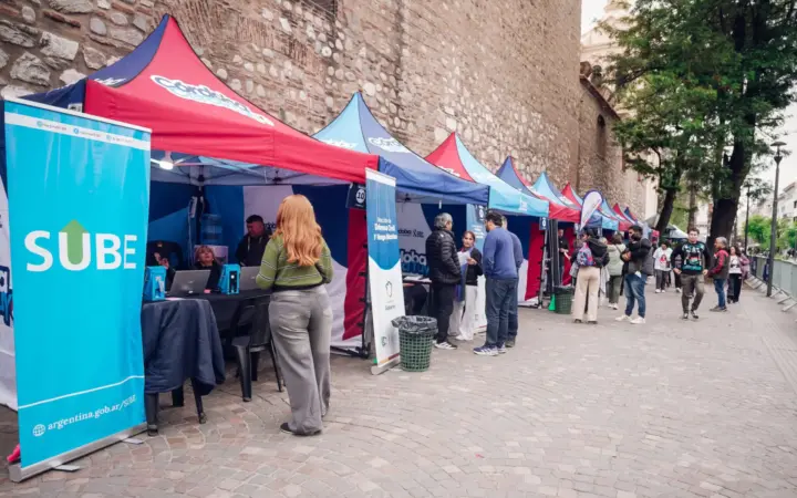 Carpas del operativo municipal instaladas sobre una calle adoquinada, con un cartel de SUBE y vecinos siendo atendidos